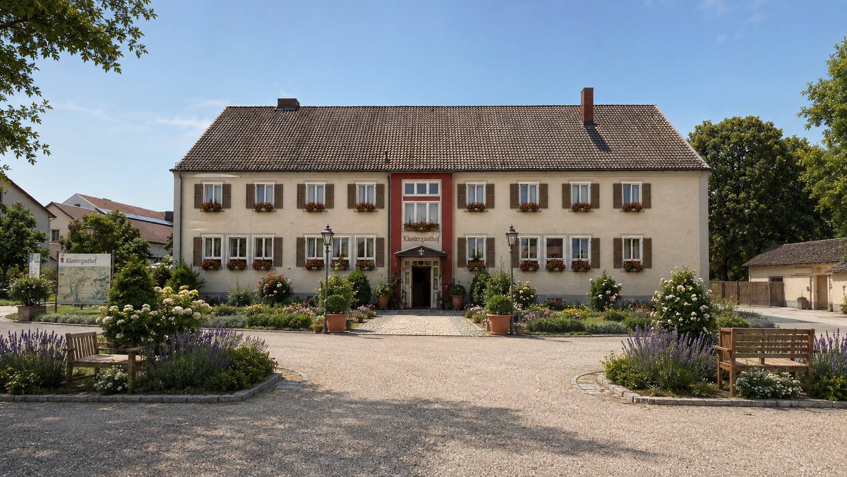 Frontansicht des Emminger Hofs in St. Ottilien mit Fensterläden, Blumenkästen und bepflanztem Vorplatz